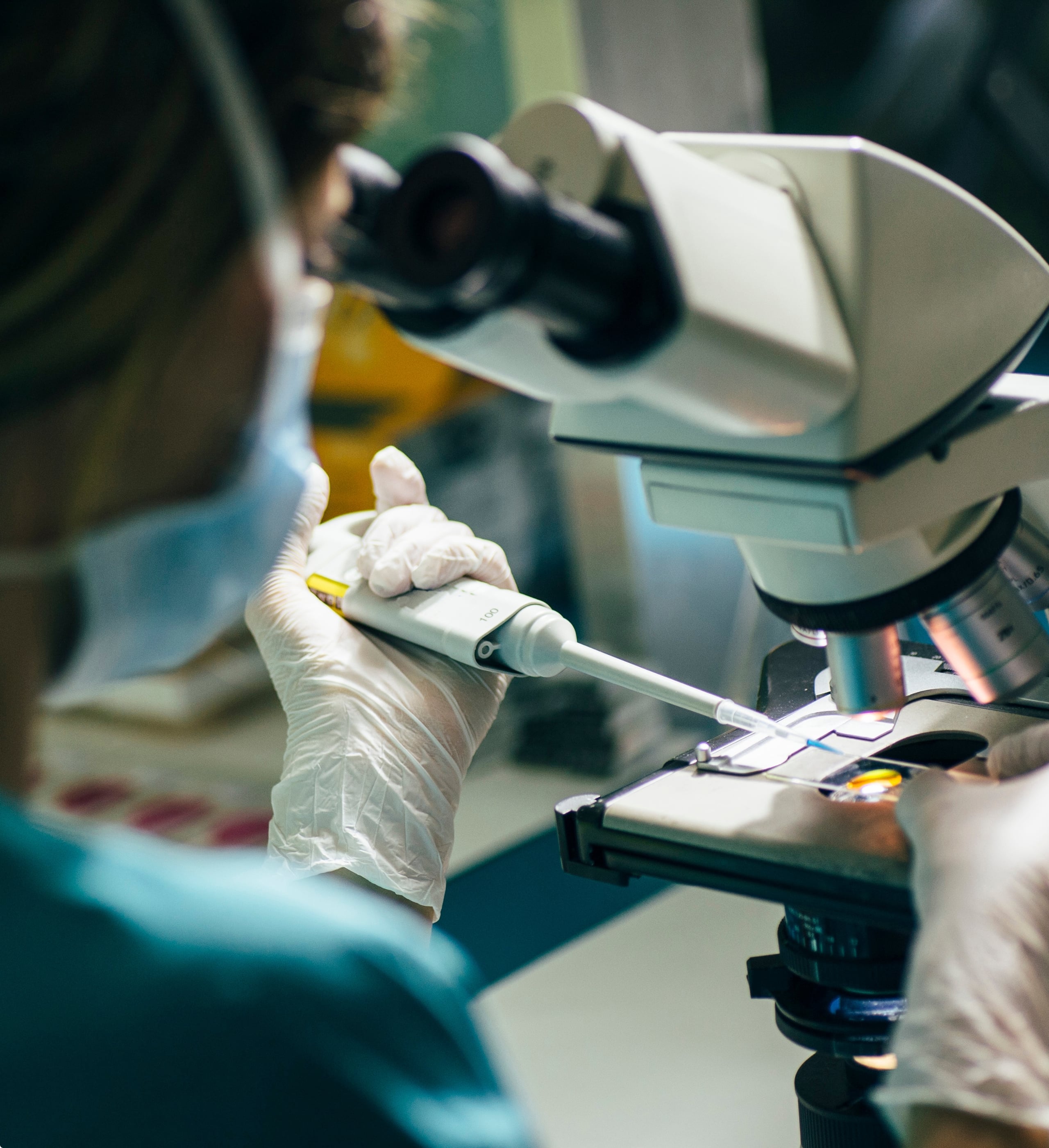 2020 milestone: US Fertility and SSI Strategy acquisition, lab technician using pipette under microscope